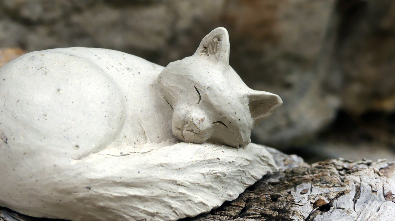 Petit chat blanc endormi en grès blanc